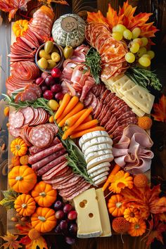 an assortment of meats and cheeses on a platter surrounded by autumn leaves