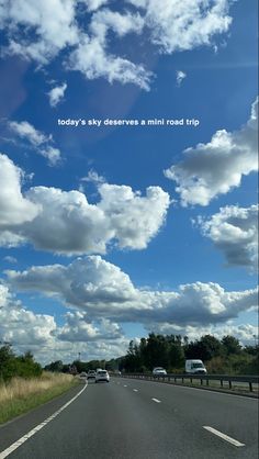 the sky is filled with clouds and there are cars driving down the road