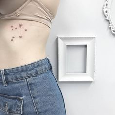 a woman's stomach with small tattoos on her left side and an empty white frame