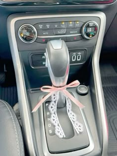 the interior of a car with an automatic gear lever and pink ribbon tied around it