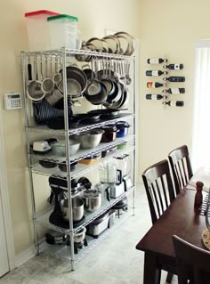 a metal rack filled with pots and pans on top of a wooden dining room table