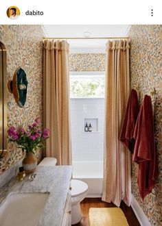 a bath room with a toilet a sink and a window next to a bath tub