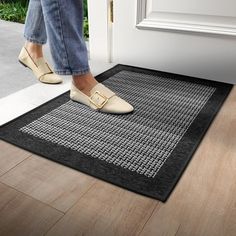 a woman stepping on a door mat in front of a house with her feet up