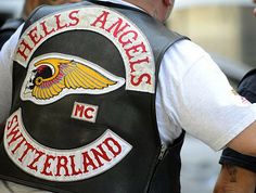 a man wearing a black leather vest with an eagle on it and the words hells angels mc switzerland