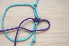 a blue and purple rope with a heart shaped knot attached to it on a wooden surface