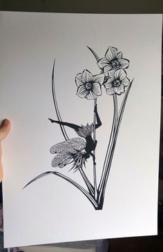 a hand holding up a black and white drawing of flowers