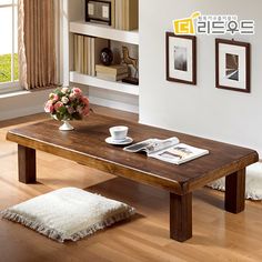 a wooden table sitting on top of a hard wood floor covered in white rugs