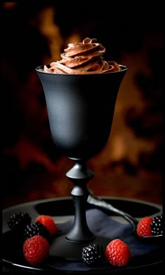 a chocolate dessert with raspberries on a black plate in front of a dark background