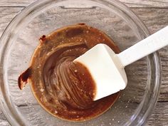 a glass bowl filled with melted chocolate and a white spatula on top of it