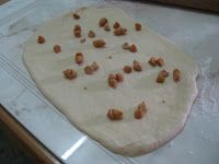 an uncooked pizza dough with nuts on it