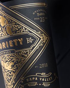 a close up of a bottle of wine with gold lettering on the front and side