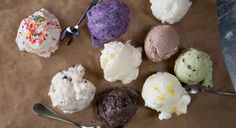 an assortment of ice creams and spoons on a piece of brown paper with sprinkles