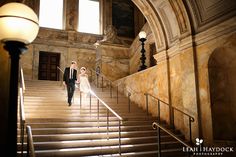 a bride and groom walking down the stairs at their wedding reception in an old building