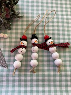 three snowmen are hanging from string on the table