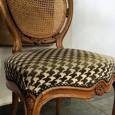 an ornate wooden chair with black and white patterned upholstered seat cover on it