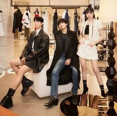 three people are sitting on a couch in a clothing store, posing for the camera