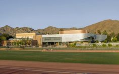 a large building sitting on the side of a road next to a field and mountains