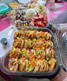 two plastic trays filled with different types of pastries and desserts on top of a table