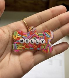 a hand holding a keychain with the word moly spelled in sprinkles