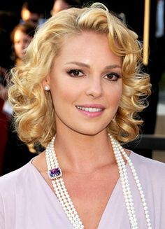 a woman with blonde hair and pearls on her neck posing for the camera at an event