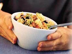 a person holding a bowl of food on top of a table