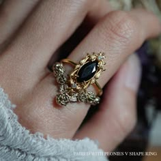 a close up of a person's hand with a gold ring on it and a black stone in the middle