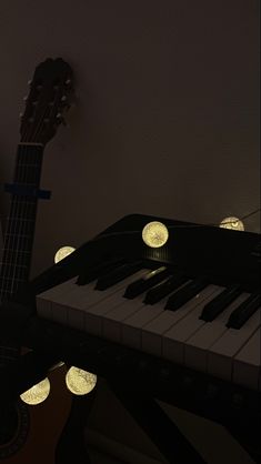 an electric piano with glowing lights on it's strings and head rests next to a guitar