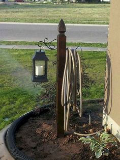 a lamp post with wires attached to it in the middle of a flower bed next to a street