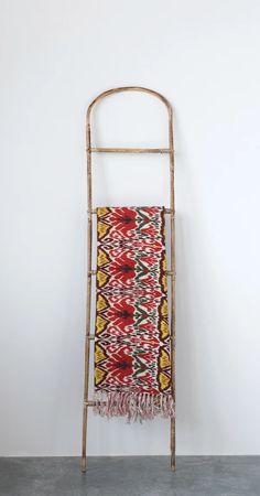 a towel rack with a multicolored blanket hanging on it's side against a white wall