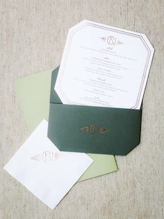 the wedding stationery is laid out on top of green envelopes and white paper