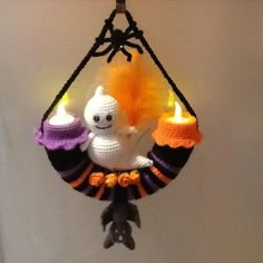 a crocheted halloween decoration hanging from a hook with candles and a ghost on it