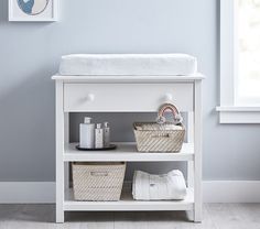 a white shelf with baskets and towels on it