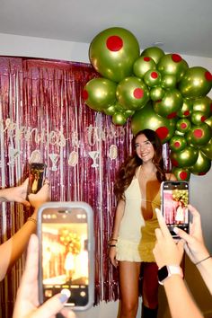 a woman is taking a photo with her cell phone while balloons are hanging in the background