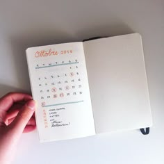 a hand holding an open notebook with a calendar on it