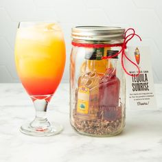 a glass filled with liquid next to a jar full of liquor and a bottle of orange juice