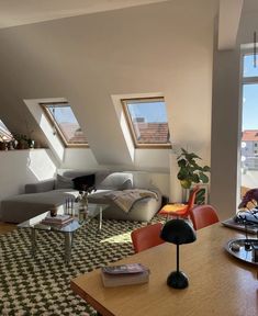 a living room filled with lots of furniture and windows next to a wooden table in front of a window