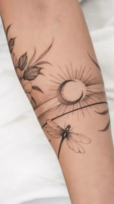 a woman's arm with flowers and a dragonfly tattoo on her left arm