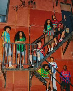 the group of young people are standing on the stairs outside an apartment building with their hands in their pockets