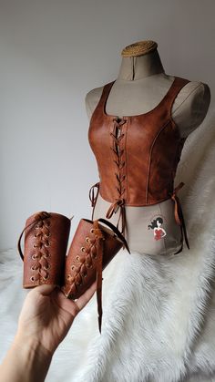 a mannequin is holding two pieces of brown leather with laces on them