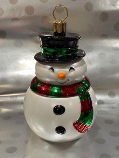 a glass ornament with a snowman wearing a hat and scarf