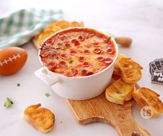 a bowl of pizza dip surrounded by chips and an egg