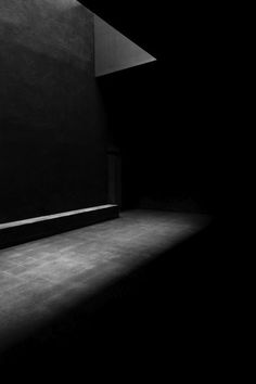 a black and white photo of a person sitting on a bench in an empty room