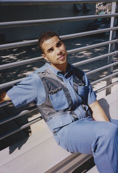 a man in overalls is sitting on a bench with his arms out and smiling