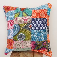 a colorful patchwork pillow sitting on top of a wooden table