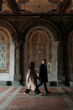 two people are walking in an old building