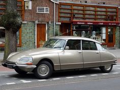 an old car is parked on the side of the road in front of a building