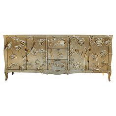 an ornately decorated dresser with gold leaf designs on the front and sides, against a white background