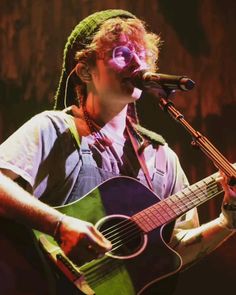 a man holding a guitar and singing into a microphone