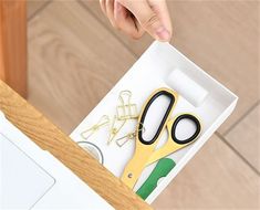 a pair of scissors sitting on top of a white box next to some paper clips