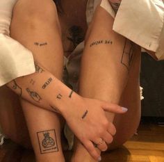 two women with tattoos on their legs sitting next to each other and holding hands together